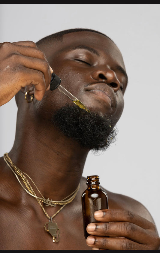close up image of a man applying "Nwabugo" Beard OIl to his beard with dropper