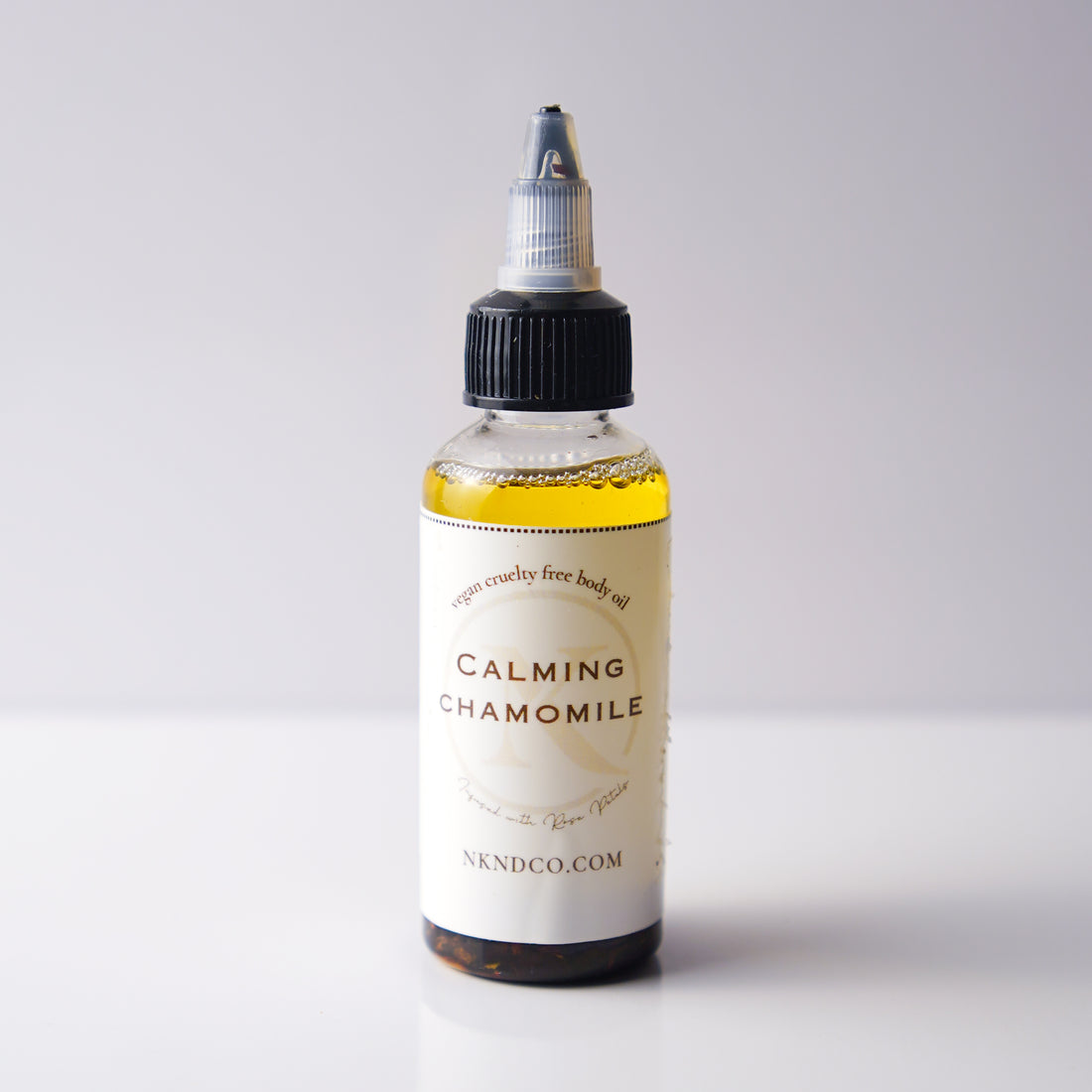 Bottle of calming chamomile oil with a white label on a light gray background