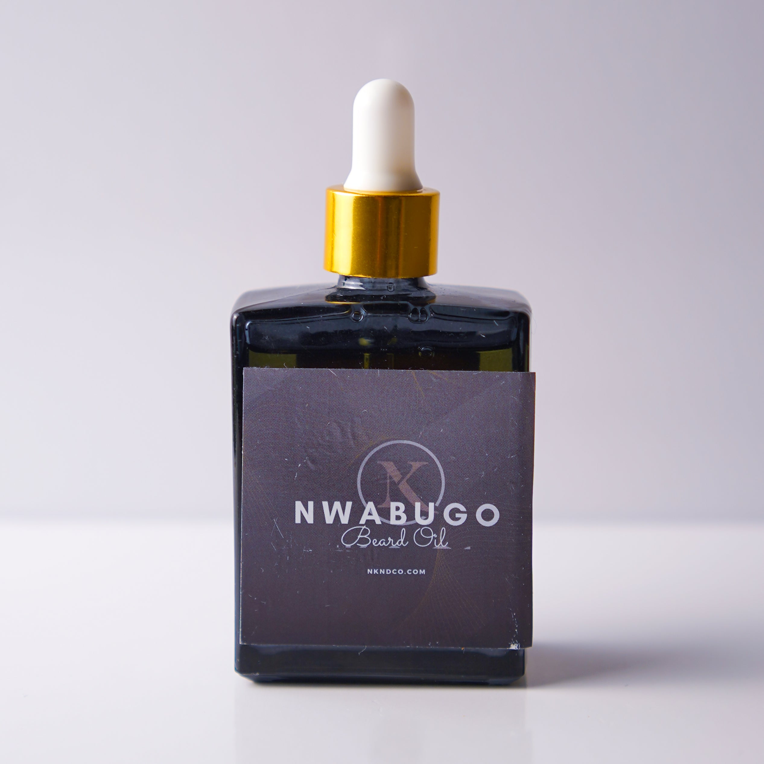 Bottle of "Nwabugo" Beard OIl with a dropper on a light gray background