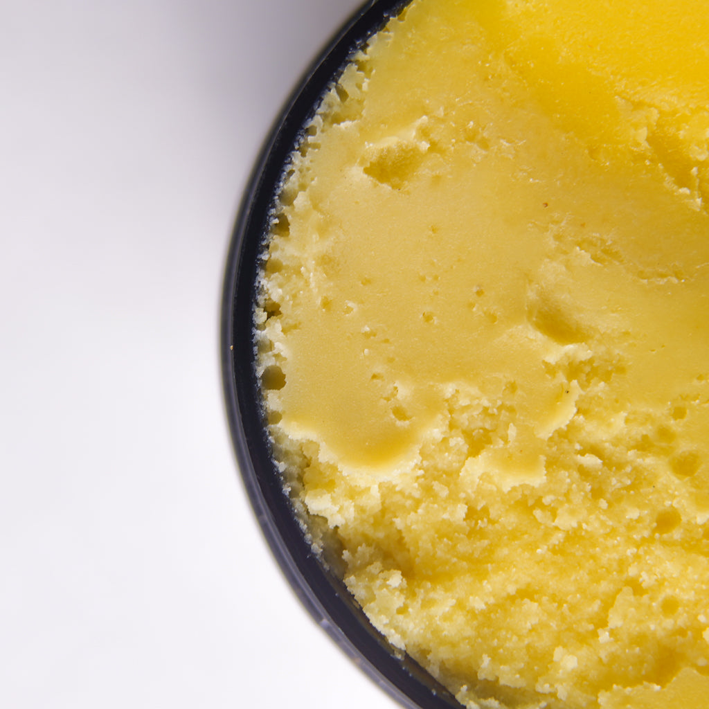 Close-up of a yellow cake texture representing "ZIkora" Hyperpigmentation Paste with a white background