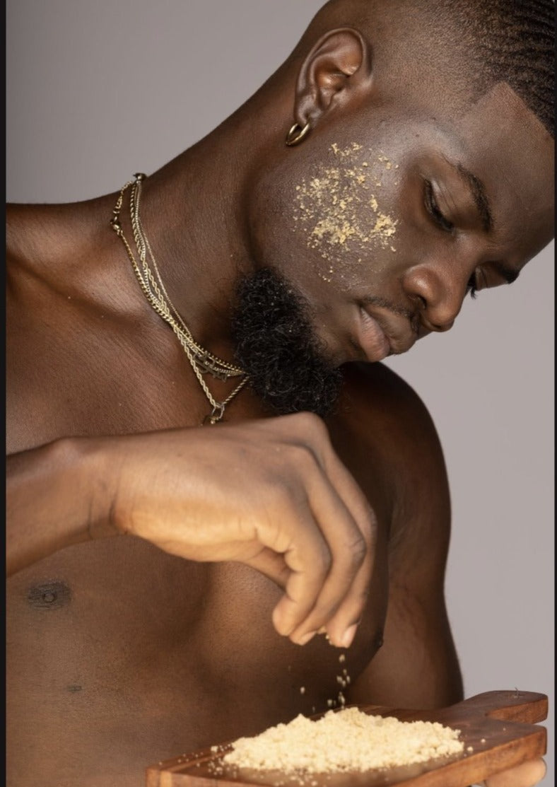 A person with a shirt lifted to reveal oatmeal scrub being applied to their face and chest.